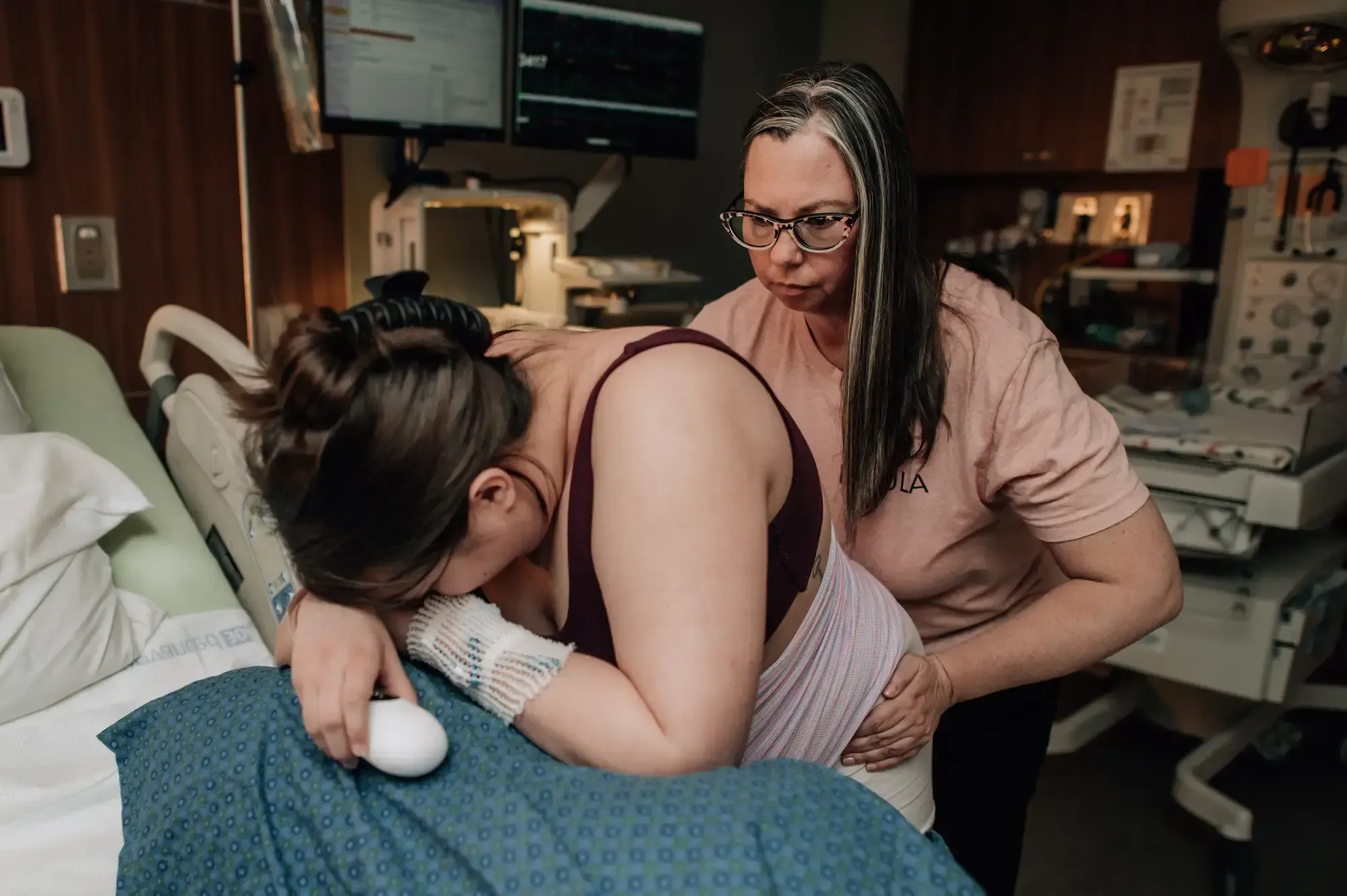Kristi providing a hip squeeze to a laboring mother in a hospital