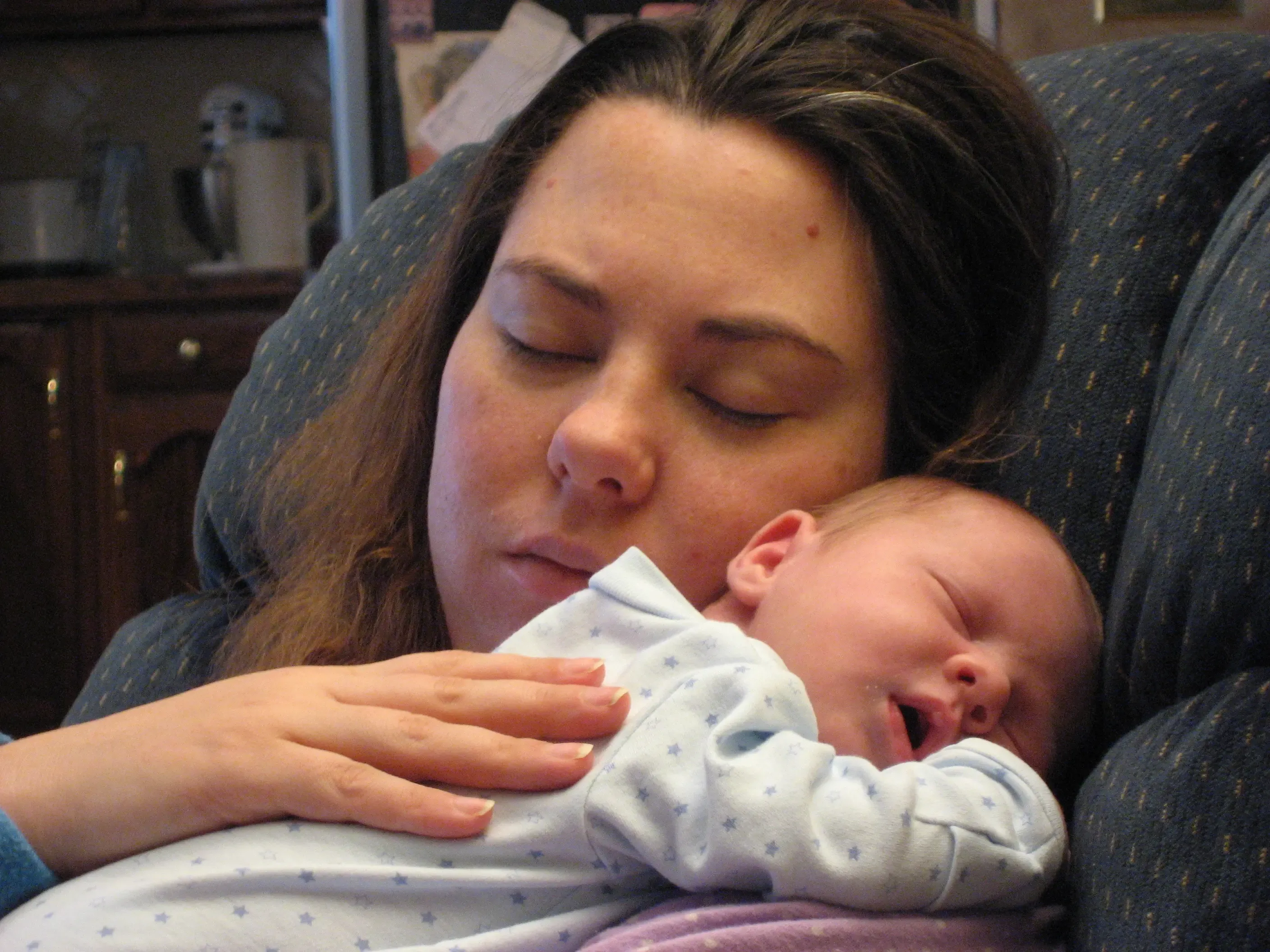 Kristi resting cheek-to-cheek with a sleeping newborn