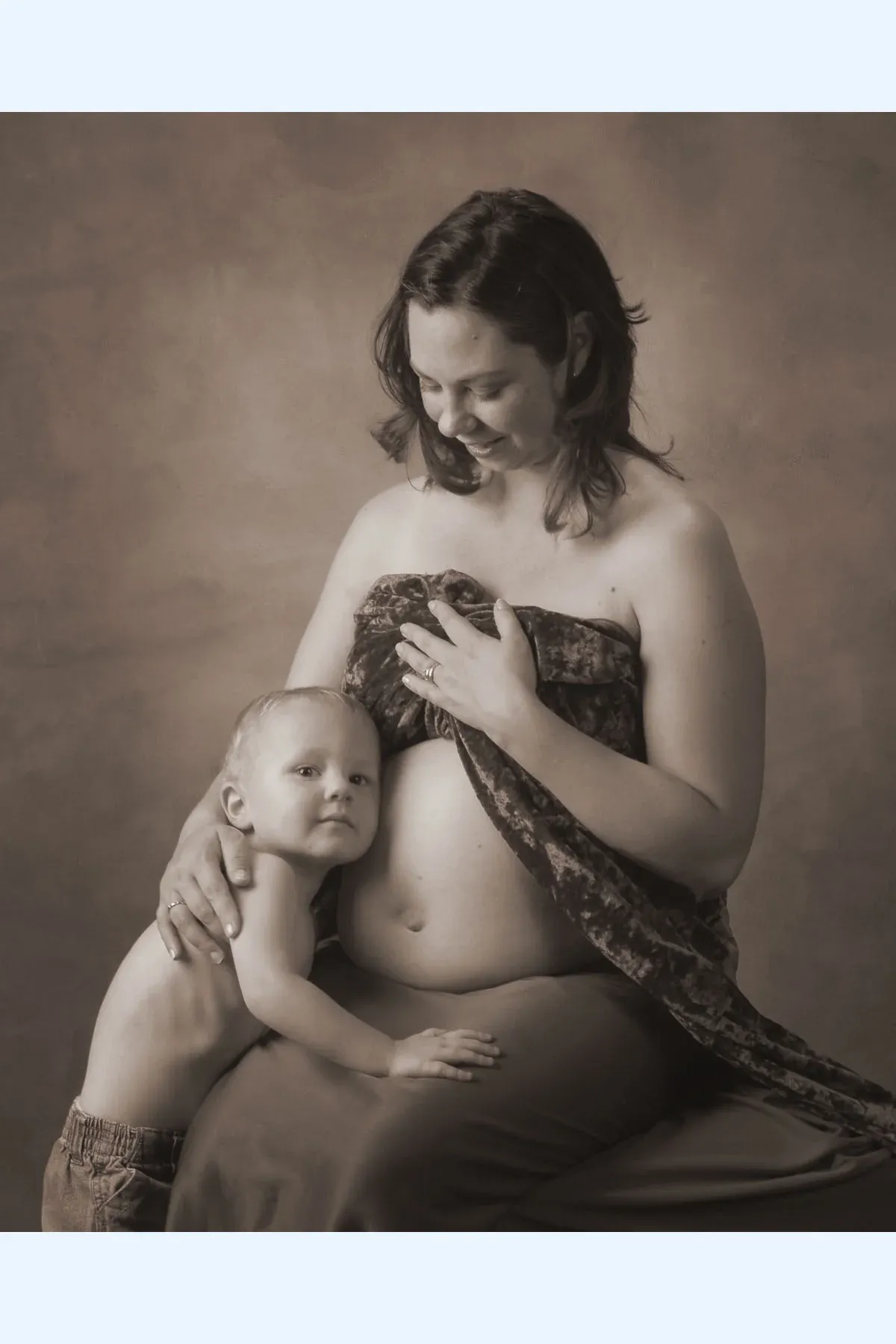 Pregnant mother and toddler in a tender studio portrait